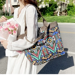 Detailed shot of ethnic tote bag featuring colorful geometric patterns and wide shoulder strap