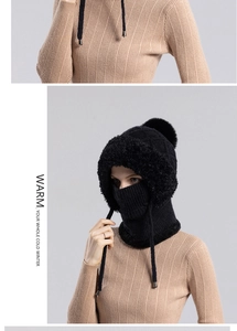 Detail of black winter knit hat with pompom and integrated neck warmer for women