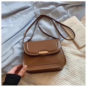Gros plan d'un sac bandoulière marron en similicuir avec un fermoir cylindrique en métal