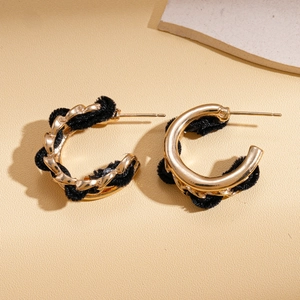 Détail de boucles d'oreilles dorées en forme de C avec tissu en velours noir d'hiver