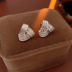 Gros plan de boucles d'oreilles triangles en argent avec zircons sur un écrin de velours