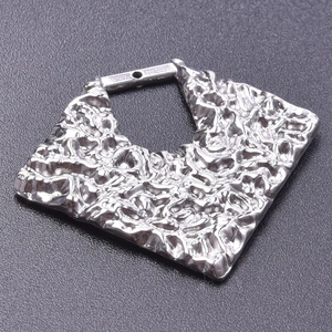 Macro shot of silver textured square metal pendant with 18k plating and molten lava finish