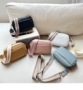 Detailed shot of five textured crossbody camera bags with colorful patterned wide straps