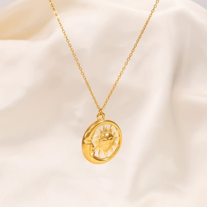 Macro shot of gold sun and moon pendant necklace on elegant white satin background
