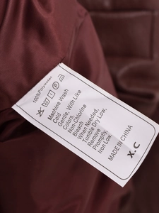 Detail des Textilpflegeetiketts mit Angabe von 100 Prozent Polyester für die Lederjacke