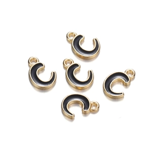 Detail of five gold horseshoe-shaped charms with black enamel finish for DIY jewelry