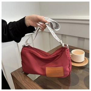 Detailed shot of a red nylon shoulder bag featuring a stylish wide patterned strap