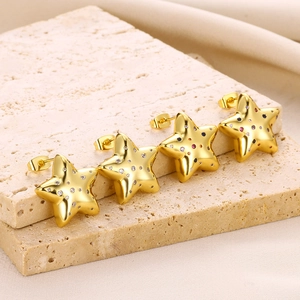 Macro shot of colorful star stud earrings with zirconia stones on a beige stone base