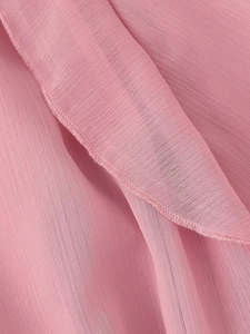 Detailaufnahme der rosa Chiffon-Stoffstruktur und der fein gesäumten Nähkanten des Kleids