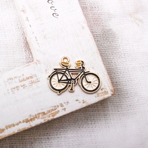 Macro shot of a vintage gold-toned bicycle pendant with enamel inlay on wooden frame