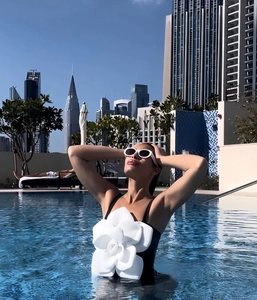 Detail of 3D white camellia flower on black one-piece swimsuit near poolside