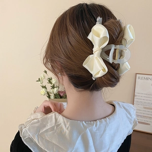 Elegant beige satin bow hair claw clip with rhinestones shown on model hair
