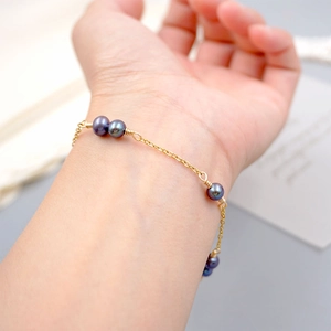Elegant gold chain bracelet with dark freshwater pearls on a woman's wrist