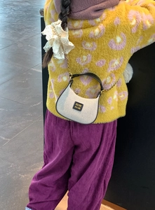 Vue détaillée d'un sac tissé pour enfants avec poignées cuir et chaîne dorée