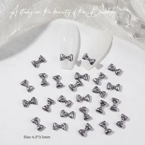 Macro detail of 3D mini bow nail charms in gunmetal silver with 6.5x3.5mm dimensions