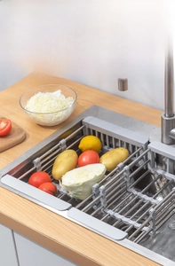 Adjustable stainless steel sink drain rack filled with fresh vegetables in kitchen