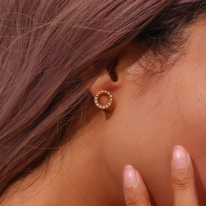 Close-up of golden twisted hoop earrings with white pearls on a model's ear