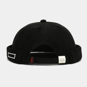 Detail of adjustable silver metal buckle and red logo tag on the black docker hat