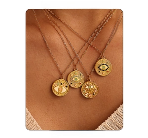 Détail de colliers dorés avec pendentifs œil porte-bonheur portés par un modèle