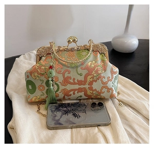 Detail of vintage brocade clutch with dragon motif, gold frame and green tassel