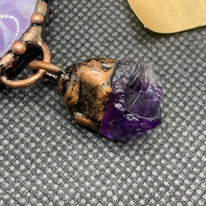 Macro shot of handcrafted vintage amethyst crystal pendant wrapped in aged copper wire