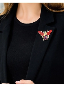 Close-up of a vintage enamel bee brooch on a black blazer lapel with colorful details