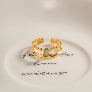 Macro detail of French vintage gold double-layer ring with inlaid green gemstone