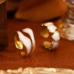 Detailed macro view of gold heart rings and wavy bands with white enamel inlays