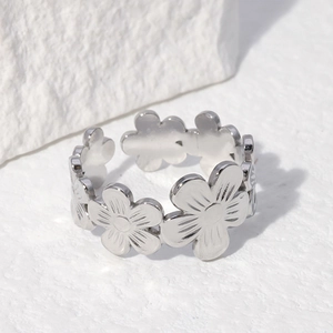 Polished silver floral open ring in stainless steel on a minimalist stone background