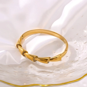 Goldenes Armband im Schlangen-Stil mit Zirkonia-Steinen auf weißem Seidenhintergrund