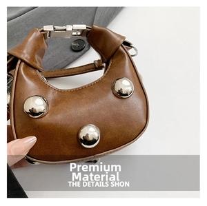 Close-up of brown leather bag with large silver studs and metallic knot handle detail
