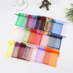 Flat lay of colorful organza drawstring gift bags with white coffee cup and Eiffel model