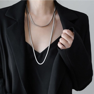 Minimalist double-layered silver snake chain necklace on female model in professional outfit