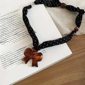 Detailed view of polka dot fabric necklace with a resin amber bow on a vintage book