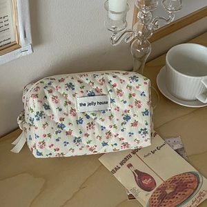 Quilted corduroy floral makeup bag with jolly house label on a wooden table