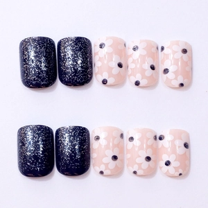 Detail of short square press-on nails with silver glitter and white daisy patterns