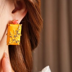Détail de boucle d'oreille émaillée vintage avec motif floral doré et pierre rose sur mannequin