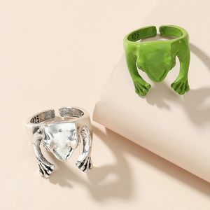 Exaggerated silver and green enamel frog open rings with 925 stamp on a beige pedestal