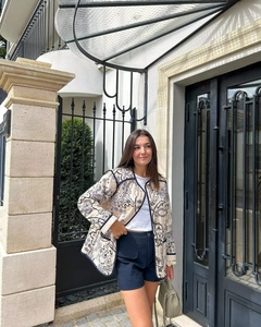 Chic beige quilted jacket with blue paisley print and contrasting trim on a fashion model