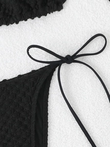 Detail of black bikini bottom featuring textured bubble fabric and adjustable side tie bows