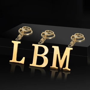 Detailed view of polished gold metal alphabet keychains with letters L, B and M