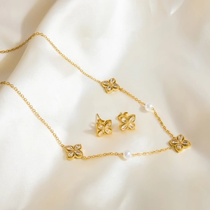 Close-up of golden four-leaf flower jewelry set with white marquise zircons and pearls