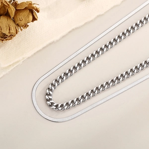 Détail du collier argenté à double rangée avec chaîne serpent et gourmette sur tissu
