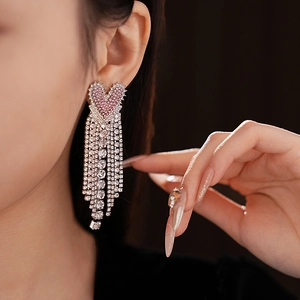 Macro shot of long heart tassel earrings with pink rhinestones on a female model