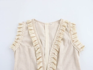 Détail de robe beige sans manches avec bordure à franges et fermeture éclair devant