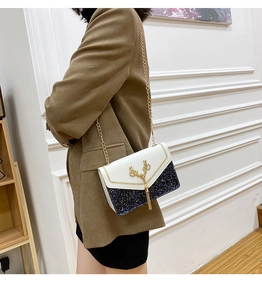 Detail einer schicken Umschlagtasche mit goldener Hirsch-Schnalle und Metallquasten