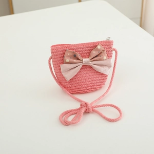Close-up of pink straw crossbody bag for kids featuring a decorative bow and zip closure