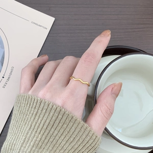Minimalist gold wavy stacking ring shown in a cozy lifestyle setting with warm tones