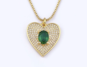 Detailed macro view of heart pendant with green gemstone and gold-plated box chain