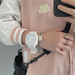 Close-up of white square digital watch with silicone strap worn with a silver chain bracelet